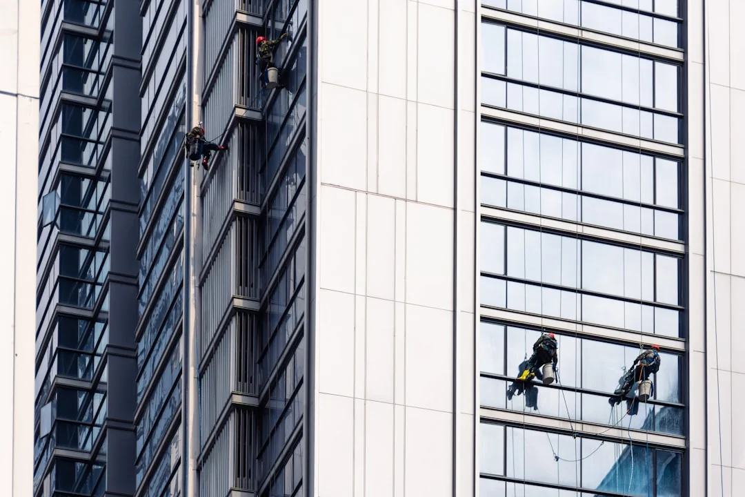 Un homme nettoie une vitre avec un mouilleur en noir et blanc, illustrant un travail professionnel.